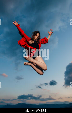 Una donna ballerina ballerina dancing in silhouette oltre il cielo nuvoloso Foto Stock