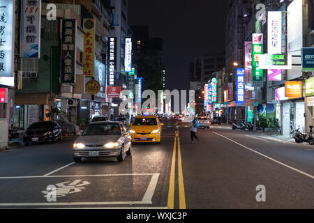 Kaohsiung, Taiwan - 07 Aprile 2019: il traffico su strada urbana notturna illuminata da colorate pubblicità insegne al neon con i caratteri cinesi. Foto Stock