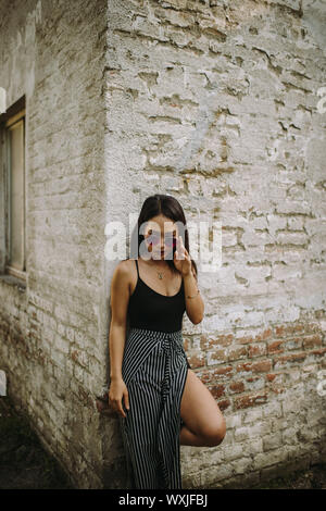 Ritratto di una giovane donna in piedi di fronte a un muro di mattoni Foto Stock