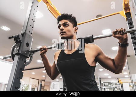 Uomo in palestra. Eseguire esercizio squatting con peso in palestra Foto Stock