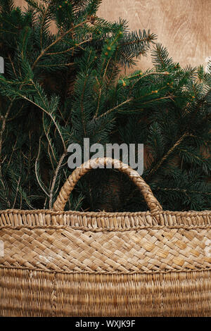 Cesto rustico con rami di abete in legno rustico sfondo. Lay piatto. Vacanze invernali preparati. Tempi di vita. Stagioni di saluto. Foto Stock