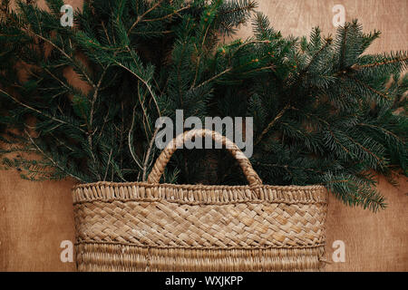 Cesto rustico con rami di abete in legno rustico sfondo. Lay piatto. Vacanze invernali preparati. Tempi di vita. Stagioni di saluto. Foto Stock