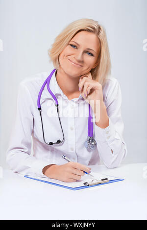 Gentile medico donna seduta al tavolo Foto Stock