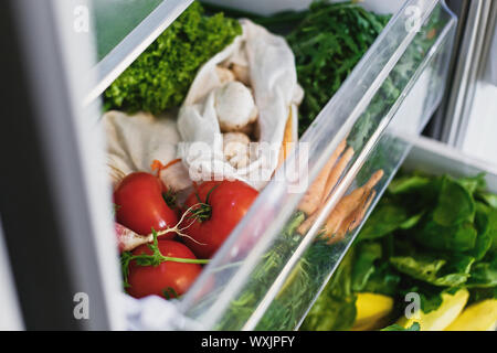 Ortaggi freschi nel cassetto aperto in frigorifero. Libero di plastica le carote, pomodori, funghi,cipolle, rafano,l'Insalata di rucola, dal mercato in frigo. Zero Foto Stock