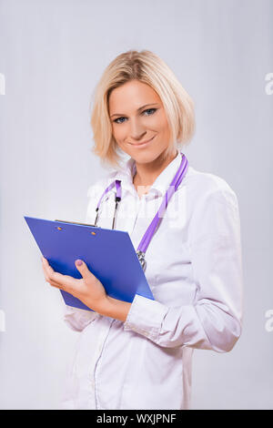 Un medico donna holding negli appunti Foto Stock