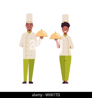 I cuochi giovane chef professionisti tenendo coperto vassoi i vassoi americano africano donna uomo ristorante lavoratori in uniforme insieme permanente Illustrazione Vettoriale