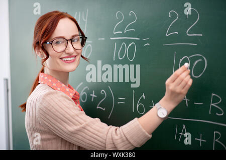 Esperto insegnante di matematica in piedi vicino a lavagna con Chalk Foto Stock