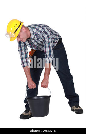 Lavoratore manuale cercando di sollevare la benna Foto Stock