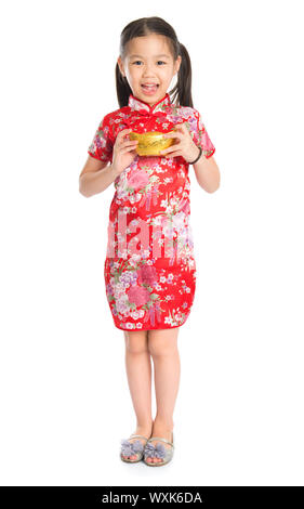 Lunghezza completa ragazza cinese in cinese tradizionale abito cheongsam saluto, tenendo un lingotto d'oro in piedi isolato su sfondo bianco Foto Stock