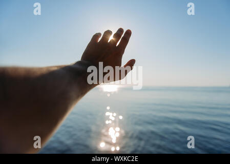 Mano d'uomo di raggiungere per sun Foto Stock