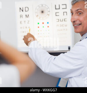 Medico sorridere mentre facendo un occhio test su un paziente in un ospedale nella sala esame Foto Stock