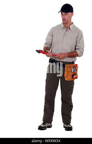 Stupito uomo in possesso di una chiave a tubo Foto Stock