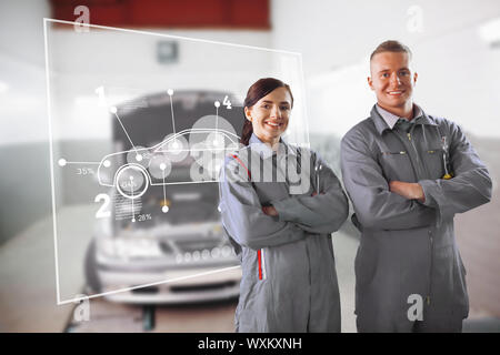 Due meccanici in piedi di fronte ad una interfaccia futuristica in un garage Foto Stock