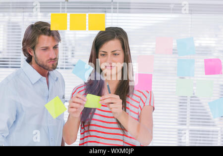 I colleghi incollando una nota adesiva in ufficio creativo Foto Stock
