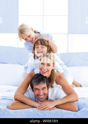 Famiglia impilati sul top del papà in camera da letto Foto Stock