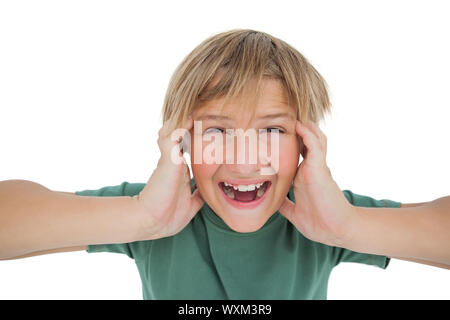 Carino ragazzo gridando e coprendo i suoi orecchi su sfondo bianco Foto Stock