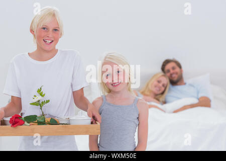 Dei bambini felici di portare la colazione a letto per i genitori Foto Stock