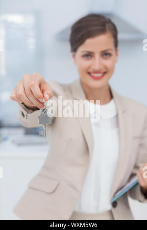 Pretty agente immobiliare offrendo chiave di casa in una cucina Foto Stock