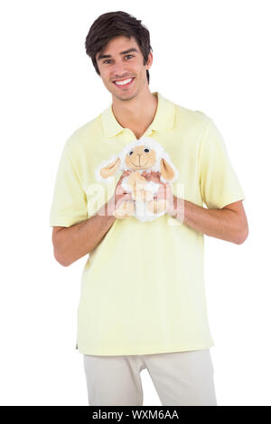 Uomo sorridente tenendo un peluche di pecora su uno sfondo bianco Foto Stock