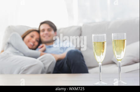 Matura in appoggio su di un lettino con flauti di champagne su un tavolo da caffè Foto Stock