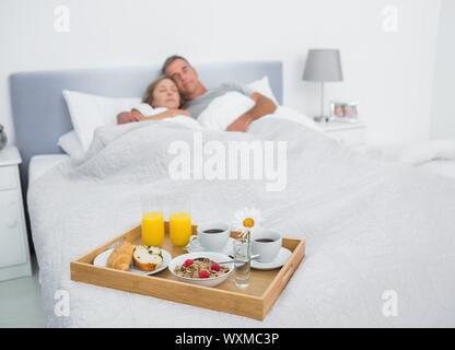 Amare giovane dormire con la prima colazione il vassoio sul letto di casa in camera da letto Foto Stock