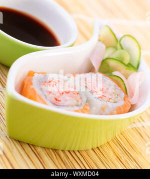 Gustosi piatti sushi con salsa di soia sul tavolo, delizioso rotolo con polpa di granchio e salmone crudo, cibo asiatico, decorato con il cetriolo e zenzero, lusso mangiare c Foto Stock