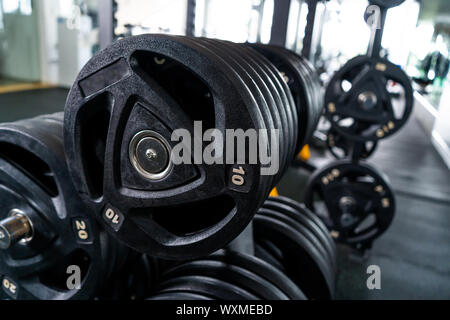 Luce moderna palestra. Attrezzature sportive in palestra. Barbells di diverso peso sul rack. Foto Stock