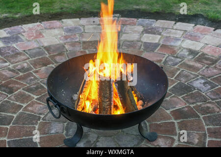 Forgiato basket fuoco con riscaldamento fuoco sulla pavimentazione bellissimo cerchio di pietra nel giardino Foto Stock