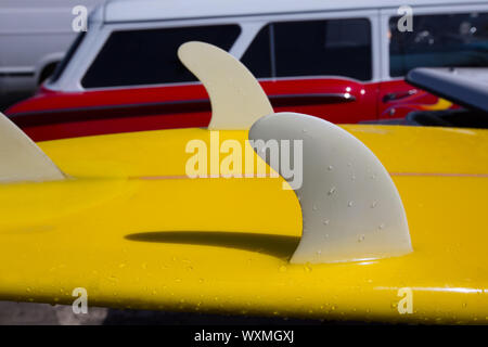 Giallo surfboard chiglia alette dettaglio eith retro rosso auto in background in California Foto Stock