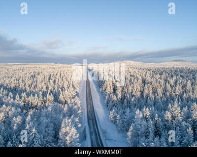 Vista aerea di una strada nel centro della vasta foresta taiga in inverno in Finlandia Foto Stock