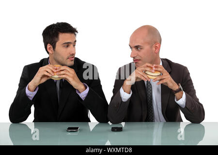 Duo di uomini di affari di mangiare hamburger Foto Stock