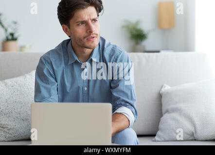 Malinconici imprenditore a Laptop pensando seduto sul lettino Foto Stock