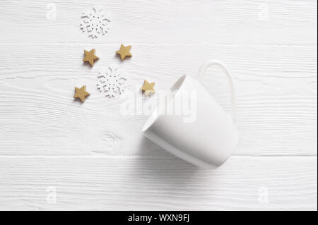 White tazza da caffè con coni di Natale e stelle. Spazio per il testo o il design. Mockup tazza bianca su un bianco sullo sfondo di legno. Piatto, laici top view foto Foto Stock