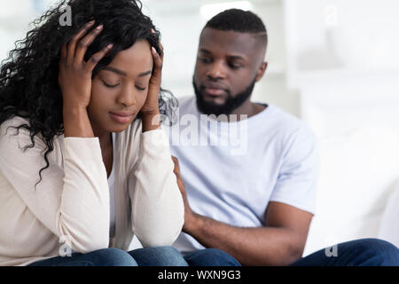 Amorevole uomo africano calmante sconvolto ragazza, scusandosi dopo litigare Foto Stock