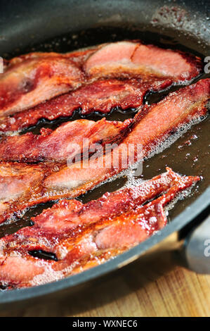 Strisce di pancetta sfrigolante su una padella Foto Stock