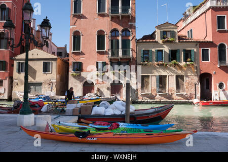 Canale di Venezia con una barca a motore d'acqua davanti a vecchi edifici Foto Stock