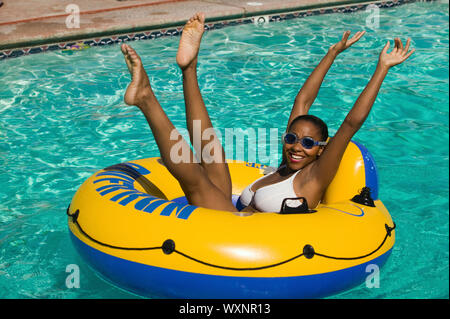 La donna solleva le braccia e le gambe sono in piscina galleggiante Foto Stock