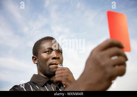 Arbitro di calcio tenendo fuori un cartellino rosso Foto Stock