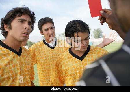 Arbitro di calcio tenendo fuori un cartellino rosso Foto Stock