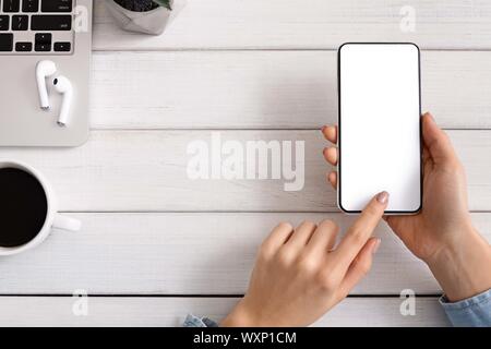 Donna che utilizza smartphone con schermo vuoto alla sperimentazione di nuove app Foto Stock