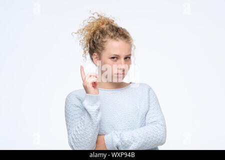 Giovani caucasici ragazza bionda che mostra il dito indice fino dare consigli. Studio shot Foto Stock