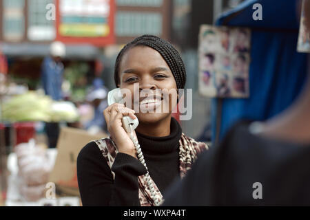 Africano o Americano nero donna chiamata su linea telefonica fissa in Alexandra township Foto Stock