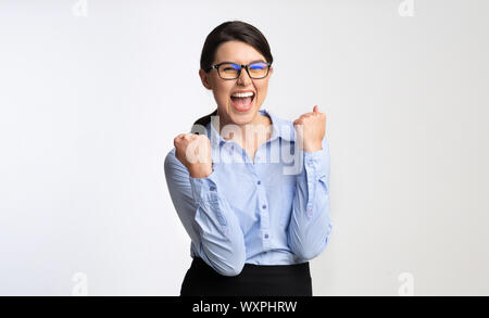 Felice imprenditrice gesticolando sì celebra il successo, sfondo bianco Foto Stock