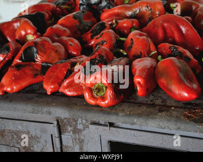 Peperoni rossi dolci arrostiti sulla vecchia in legno nero e fornello. Dolci al forno di pepe rosso Foto Stock
