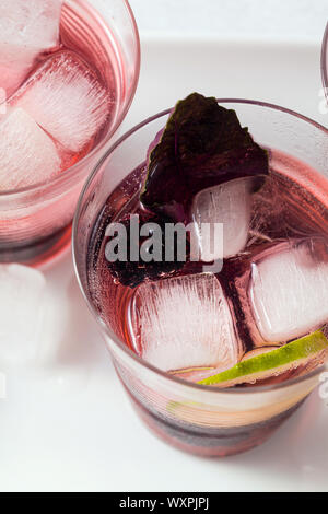 Il gin tonic con more e foglie di basilico viola. estate cocktail rinfrescante Foto Stock