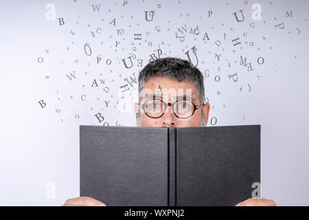 Uomo con occhiali in possesso di un notebook con stupore sul suo volto con lettere in aria su uno sfondo bianco. Foto Stock