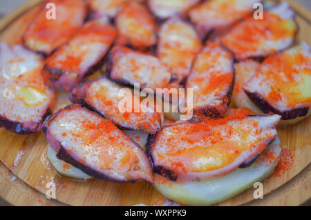 Fette di polpo grigliate con pimento paprika in polvere e patate a fette su un piatto di legno rotondo Foto Stock