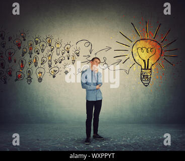 Casual studente ragazzo adolescente, volto fiducioso espressione, tenendo la mano al mento come il pensiero di nuove idee di raccolta ad essi per creare un piano finale. Ingeni Foto Stock