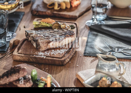 Barbecue carni bovine t-bone steak servita su legno piatto con vino e verdure grigliate Foto Stock