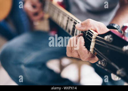 Mano d'uomo le suonando una chitarra elettrica. Messa a fuoco selettiva. Copia dello spazio. Foto Stock